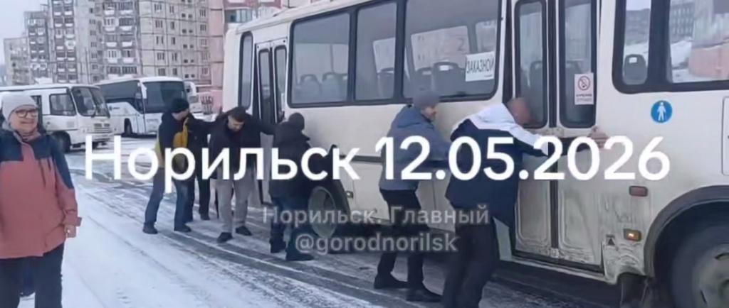 Люди зимой толкают застрявший автобус
